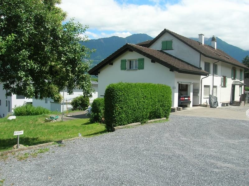 2 story house, white exterior, green shutters, brown roof, garage, gravel driveway, mountain view