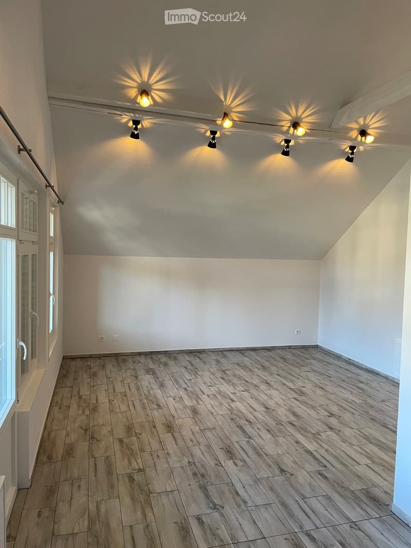 Empty room with wooden flooring, white walls, and recessed lighting fixtures. Features a door with glass panels and a window on one side.