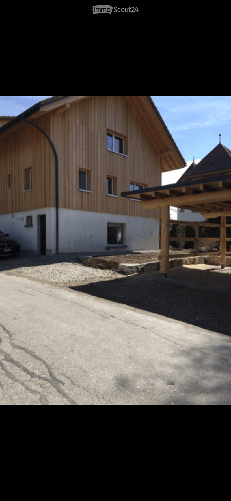 2 story house, wooden exterior, white walls, multiple windows, car parked in front, wooden structure in front