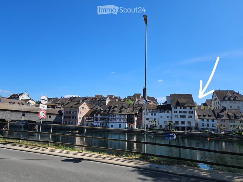 A scenic view of a town with traditional houses along a canal, featuring a clear blue sky and calm water.
