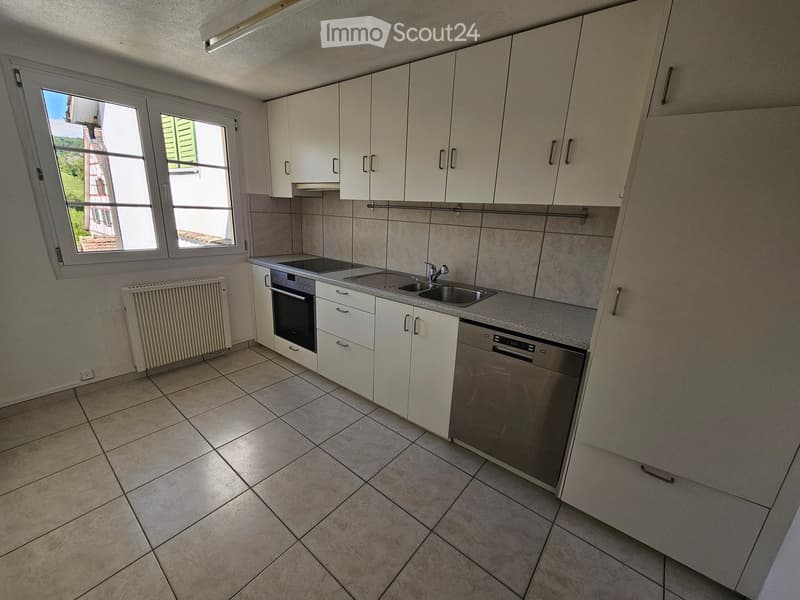 Modern kitchen with white cabinets, stainless steel appliances, tiled floor, and a window offering a view.