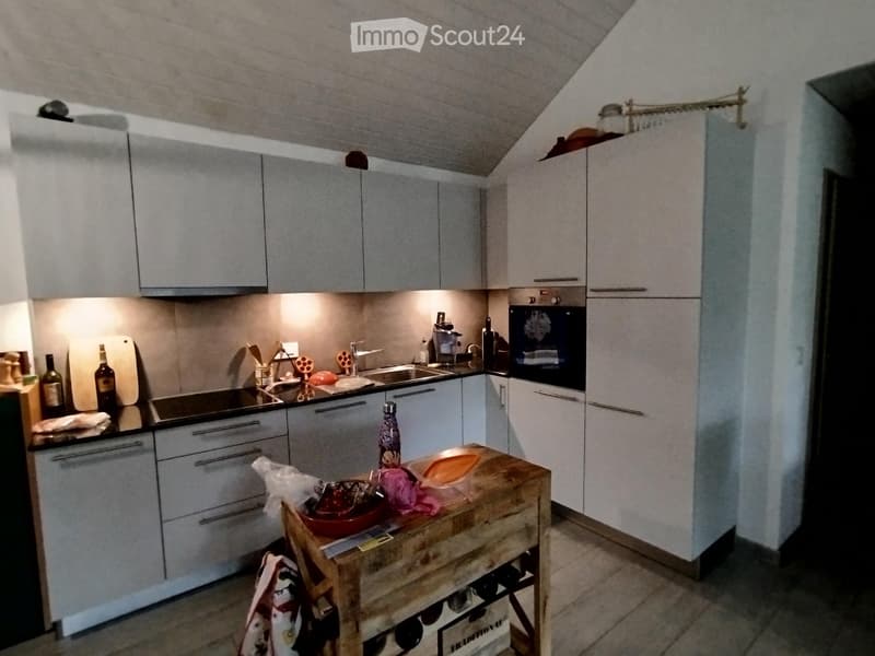 Modern kitchen with white cabinets, stainless steel appliances, and a wooden island with various items on top.