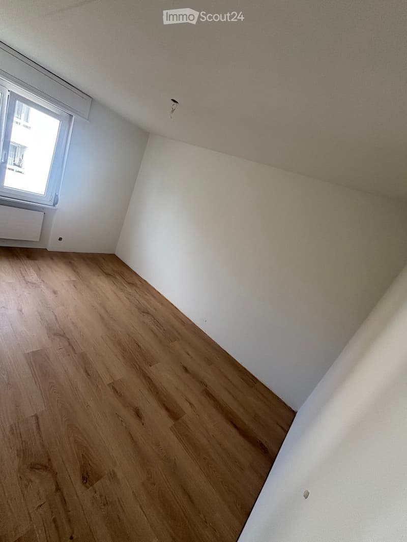 Empty room with wooden flooring and white walls, featuring a window with a radiator below it.