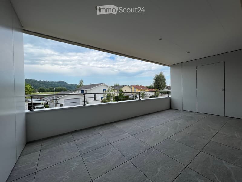 Modern balcony with tiled floor, metal railing, and expansive view of the surrounding neighborhood and hills.