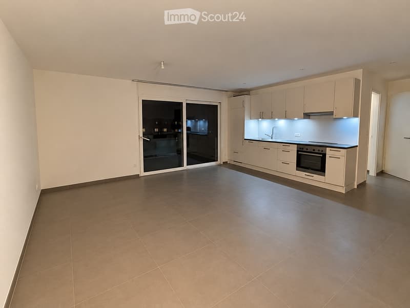Modern kitchen with light-colored cabinets, a built-in oven, a sink with a faucet, and a sliding glass door leading to another room.