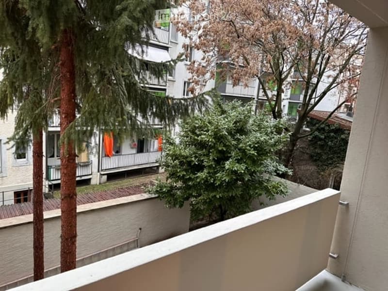 Balcony overlooking a residential area with trees, neighboring buildings, and laundry hanging on a line.