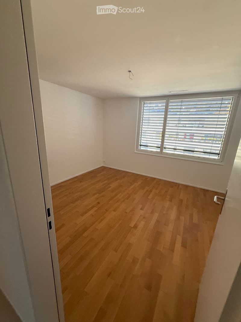 Empty room with wooden flooring, white walls, and a window with blinds. No furniture or equipment present.