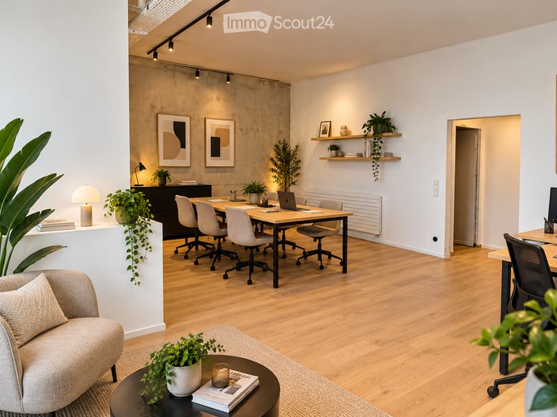 Modern, open-plan living and working space with a sofa, coffee table, laptop on a desk, chairs, shelves with books and plants, and a large potted plant near the sofa.