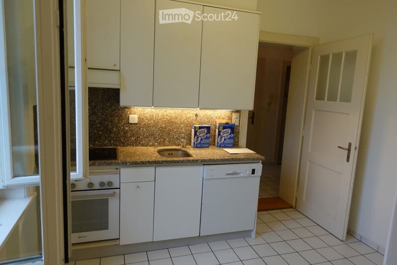 Modern kitchen with white cabinets, granite countertop, sink, oven, and dishwasher. Two boxes of Tandem milk are placed on the counter.