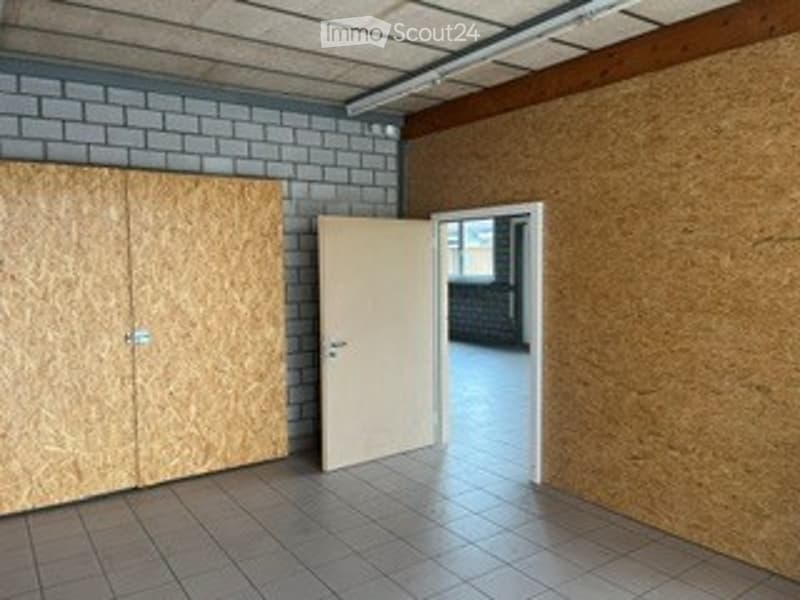 Empty room with tiled floor, exposed brick wall, and wooden cabinetry. No furniture or equipment present.