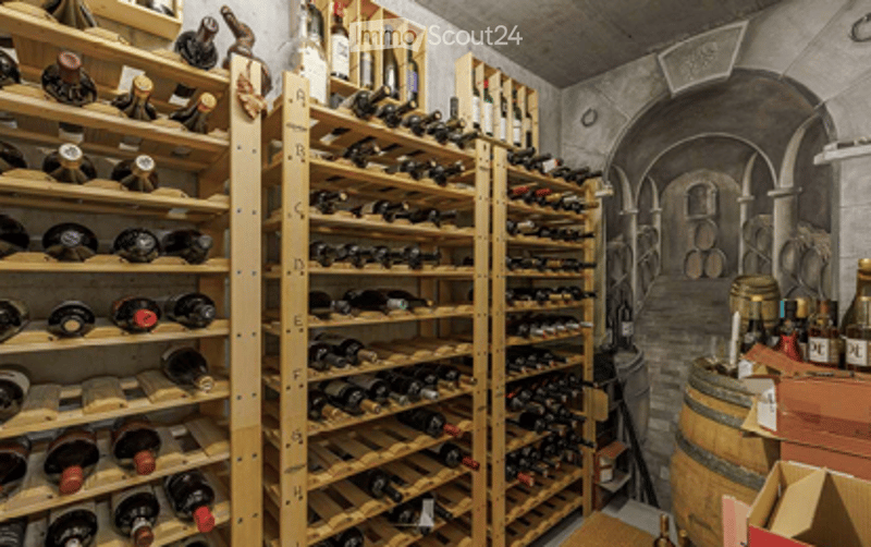 Wine cellar with wooden racks filled with wine bottles, a large wooden barrel, and a small table with a chair.