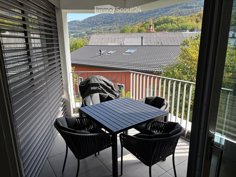 Balcony with a view of the surrounding landscape, featuring a black table and four black chairs.
