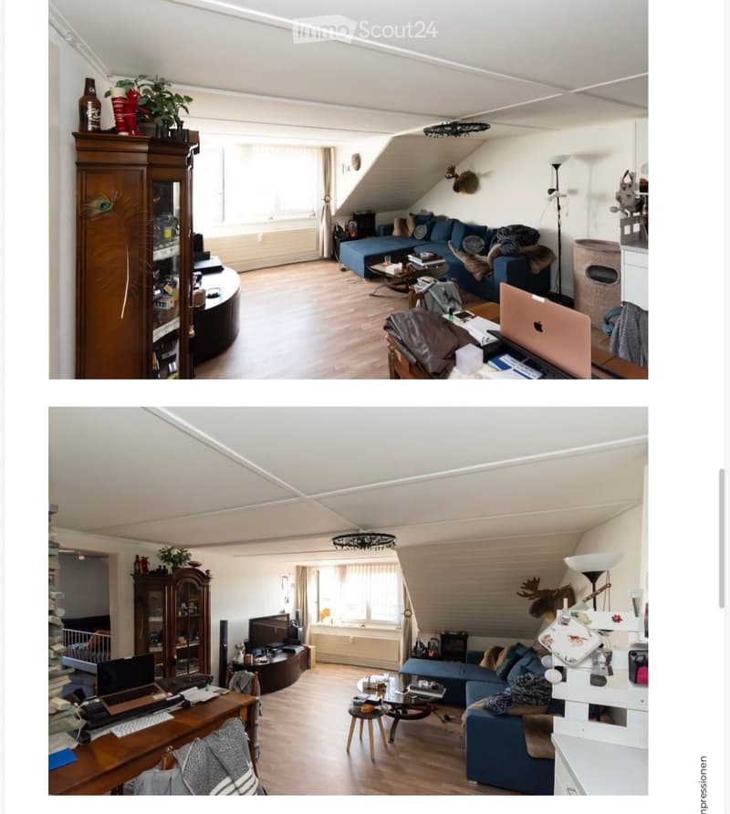 A cozy attic living room with wooden flooring, slanted ceilings, and large windows. Features a blue sectional sofa, coffee table, laptop, wooden cabinet, and a cat tree.