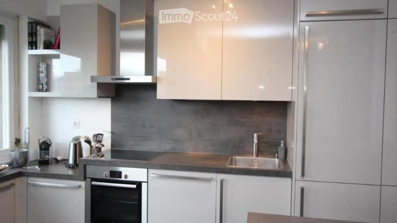 Modern kitchen with white cabinets, stainless steel appliances, and a dark grey backsplash.