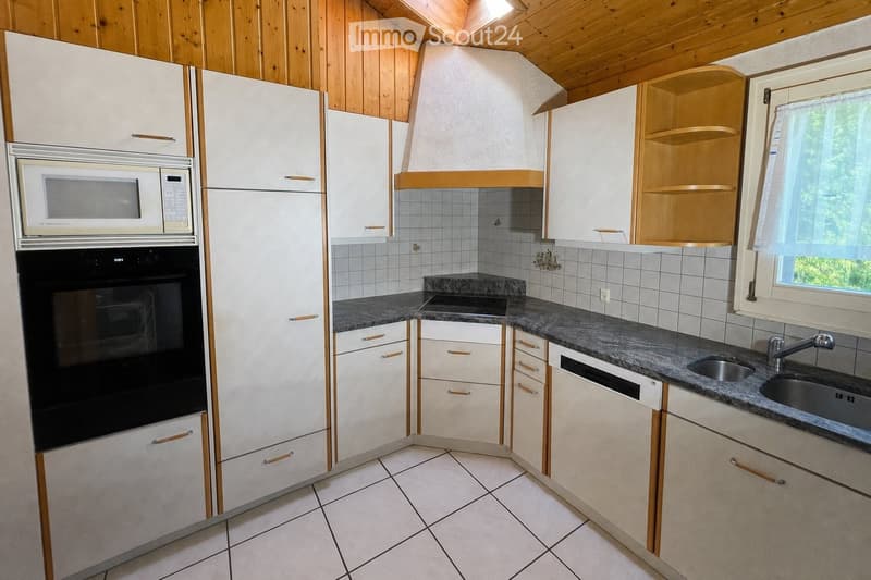 Modern kitchen with white cabinets, granite countertops, stainless steel sink, microwave, and oven. Wooden ceiling and tiled floor.