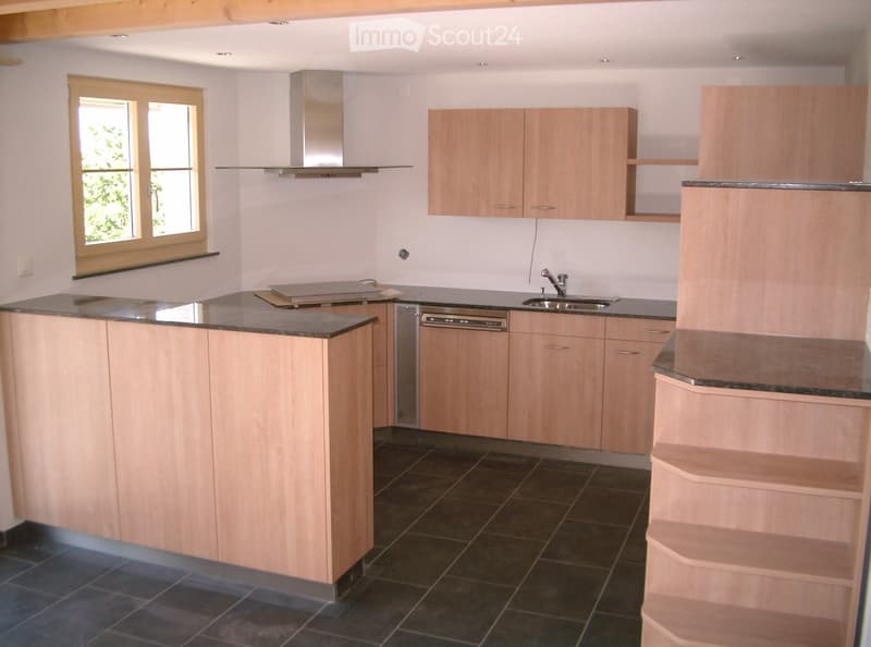 Modern kitchen with light wooden cabinets, granite countertops, island, sink, dishwasher, and range hood.