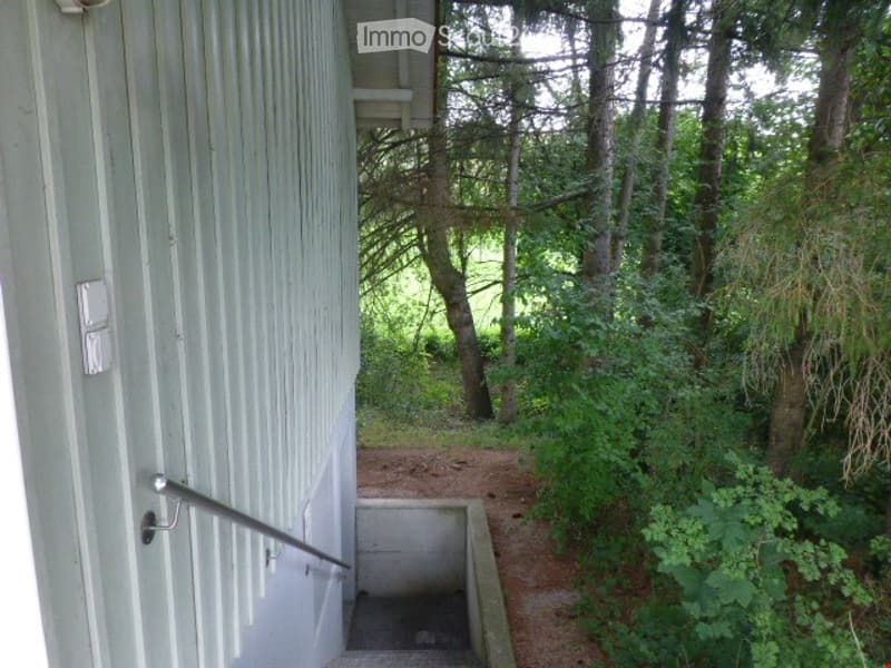 A narrow concrete staircase leading up to a raised ground floor, flanked by a metal handrail and surrounded by dense greenery and trees.