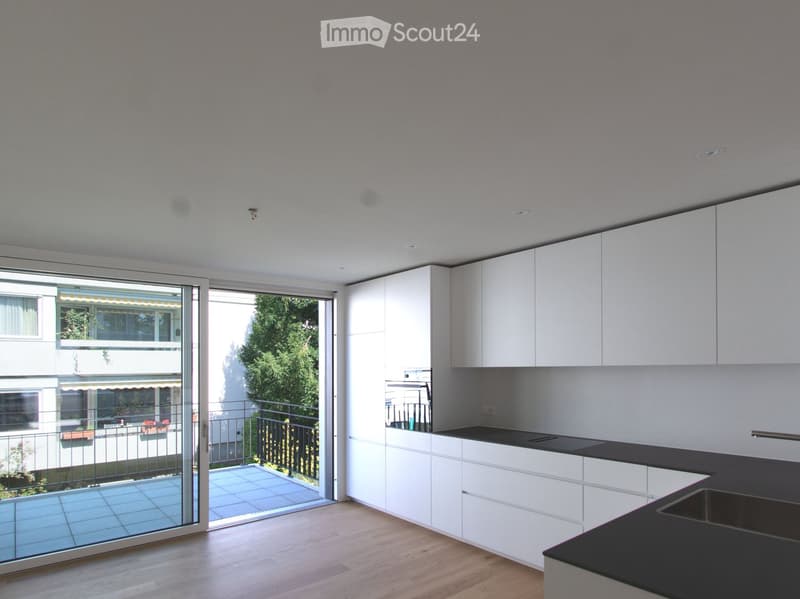 Modern kitchen with white cabinets, black countertop, and a large sliding glass door leading to a balcony.