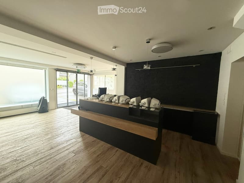 large, open space with wooden floor, modern reception desk, black walls, glass windows