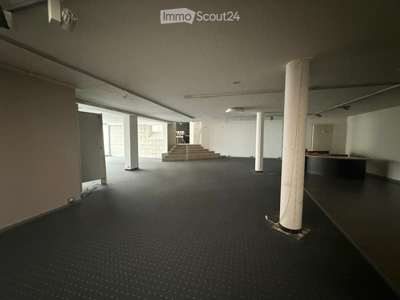 empty large room, black floor, white walls, pillars, empty stairs, closed door