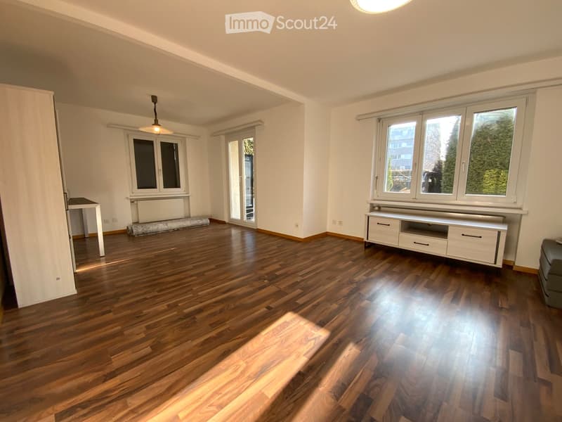 Wooden floor, two windows, a sliding door, ceiling lamp, an entertainment center, wooden furniture, daylight