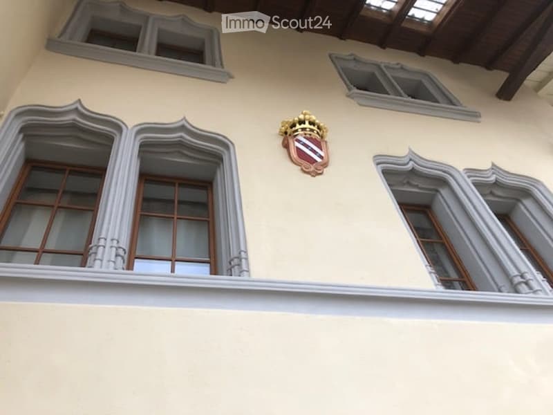 Facade with beige walls, three arched windows, and a coat of arms
