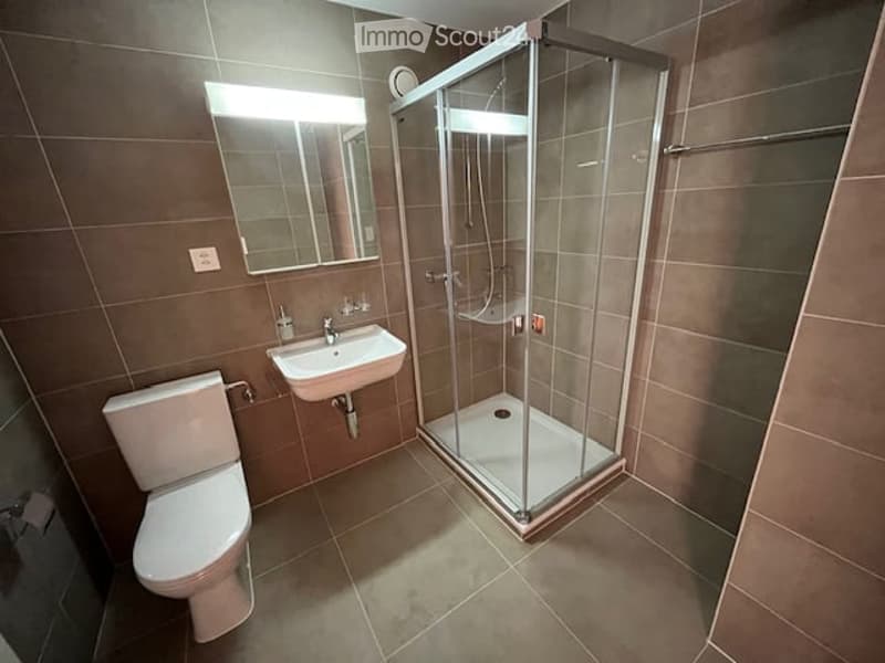 Modern bathroom with a toilet, sink, mirror, and glass-enclosed shower stall.