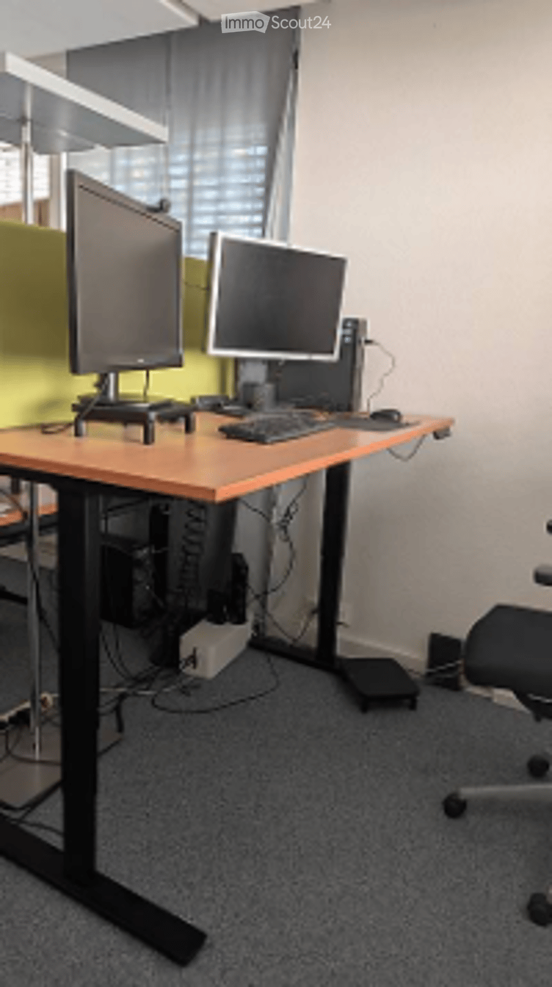 Modern office setup with a standing desk, two computer monitors, keyboard, mouse, and a comfortable office chair.