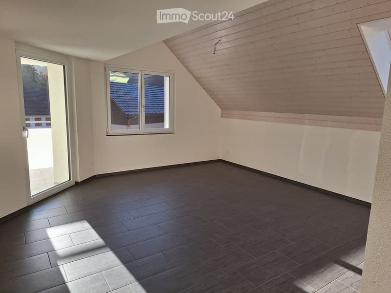 Empty room with wooden flooring, large windows, and a sliding door leading outside.