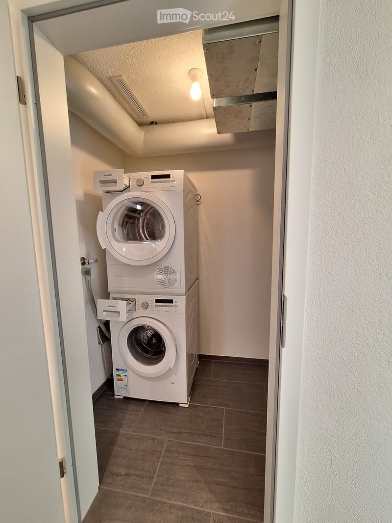 Compact bathroom with a stacked washing machine and dishwasher unit, tiled floor, and white walls.