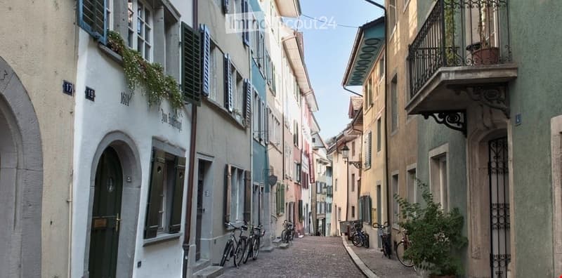 Narrow cobblestone street lined with colorful buildings, featuring bicycles parked along the sides and small balconies with potted plants.