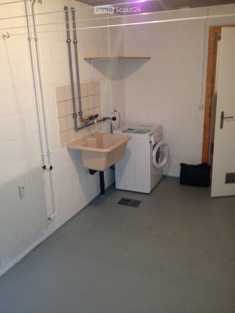 Small room with sink, washing machine, floor drain, and radiator