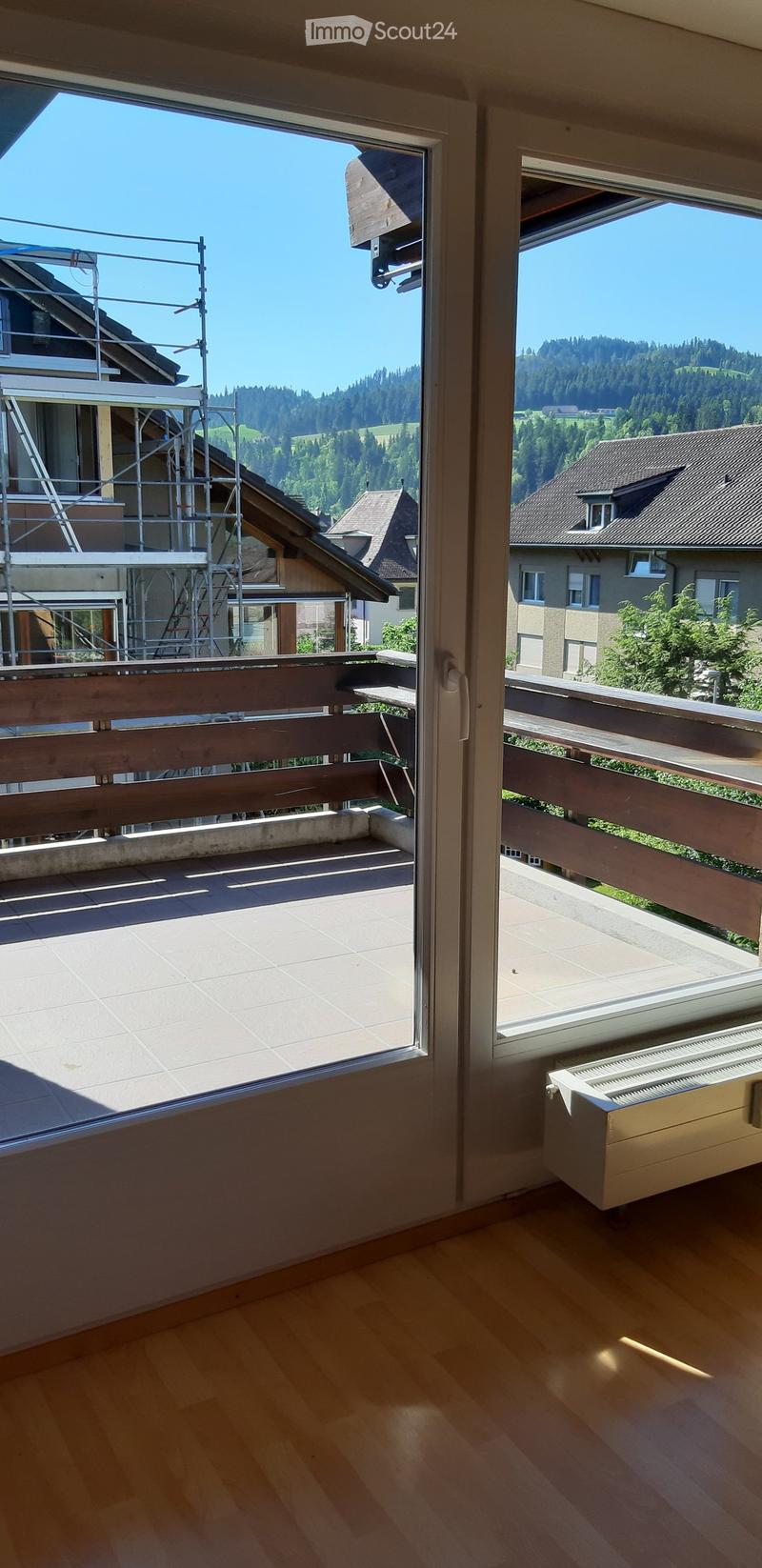 Balcony with wooden railing, tiled floor, and scenic mountain view.