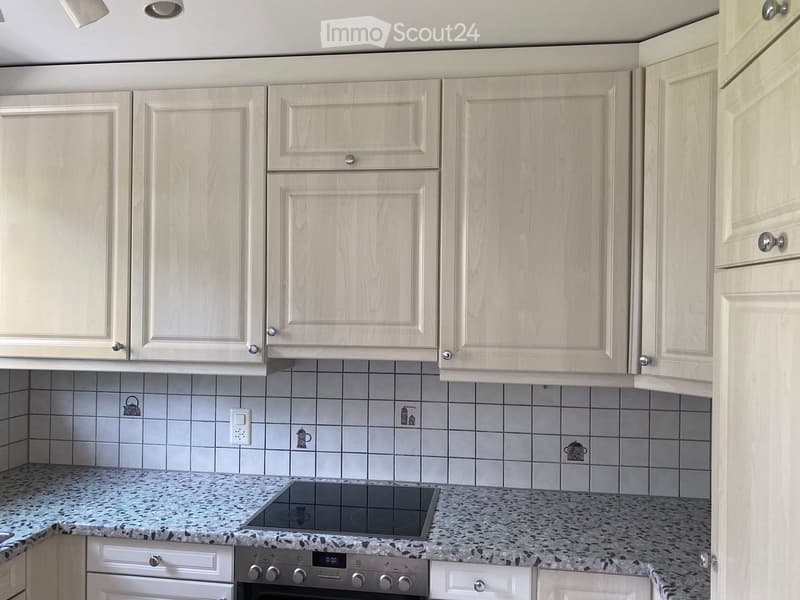 Light-colored kitchen with white cabinets, granite countertop, and built-in electric stove.