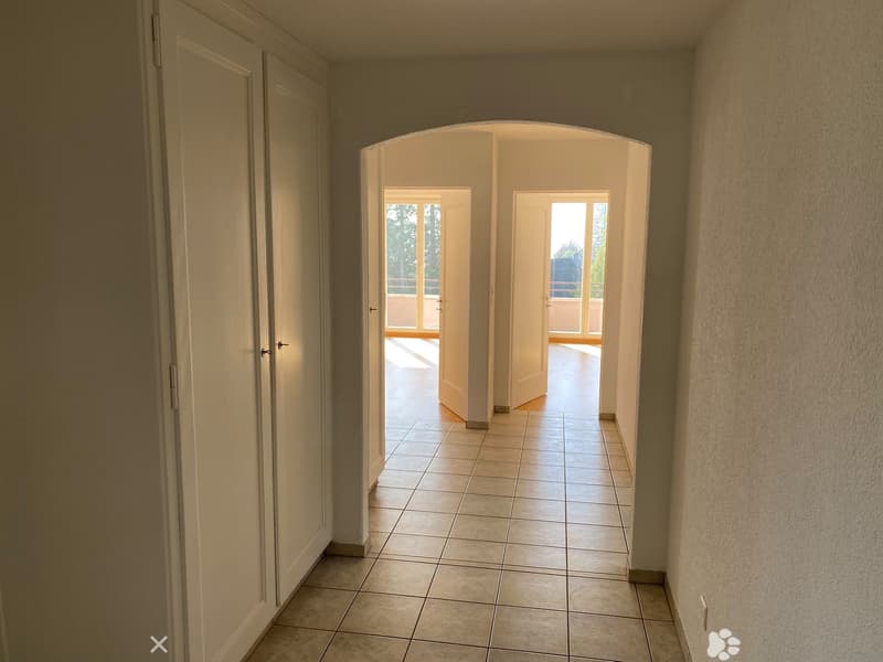 Empty hallway with tiled floor, white walls, and two open doors leading to balconies.