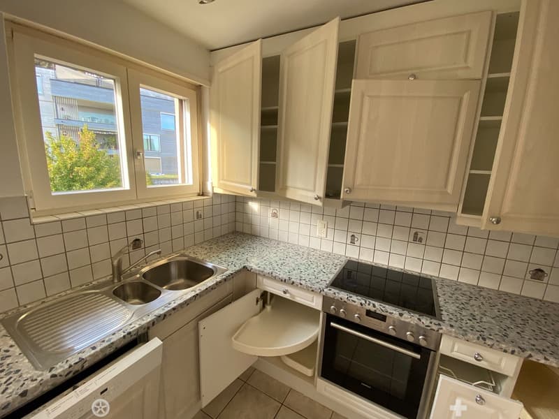 Modern kitchen with white cabinets, granite countertops, stainless steel sink, oven, and dishwasher.