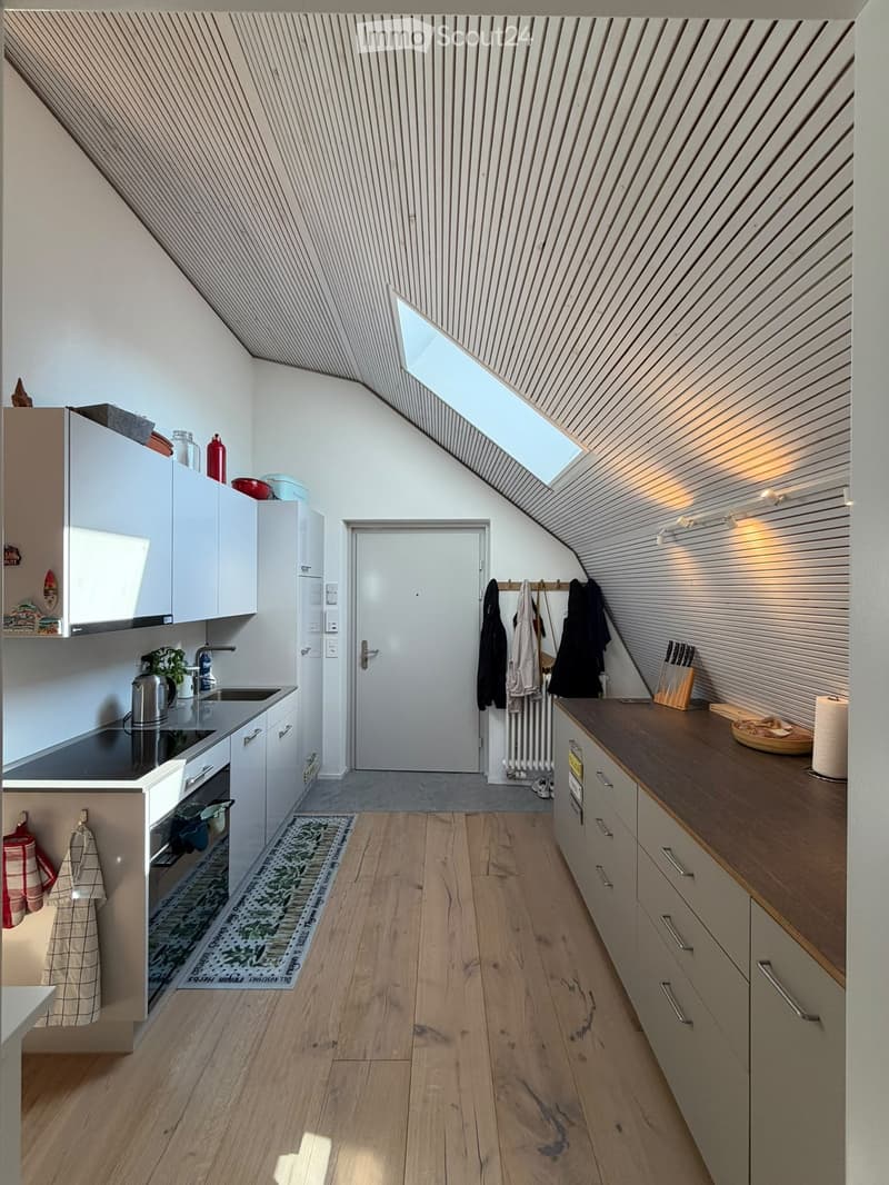 Modern kitchen with white cabinets, wooden countertops, and a skylight above. Includes a sink, stove, oven, and various kitchen items.
