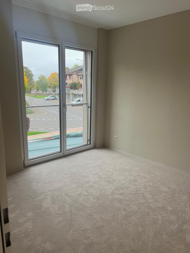 Empty room with carpeted floor and large sliding glass door leading to an outdoor area.