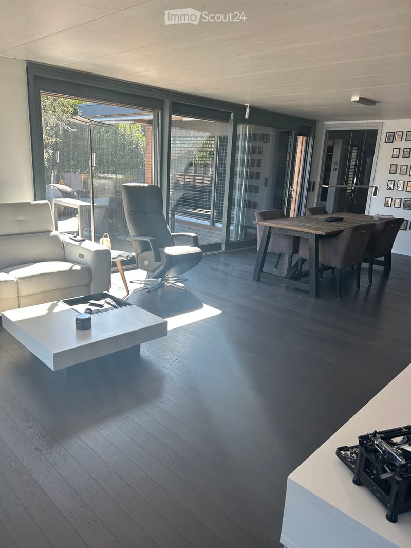 Modern living and dining area with dark wood flooring, white sofa, coffee table, dining table, and chairs.