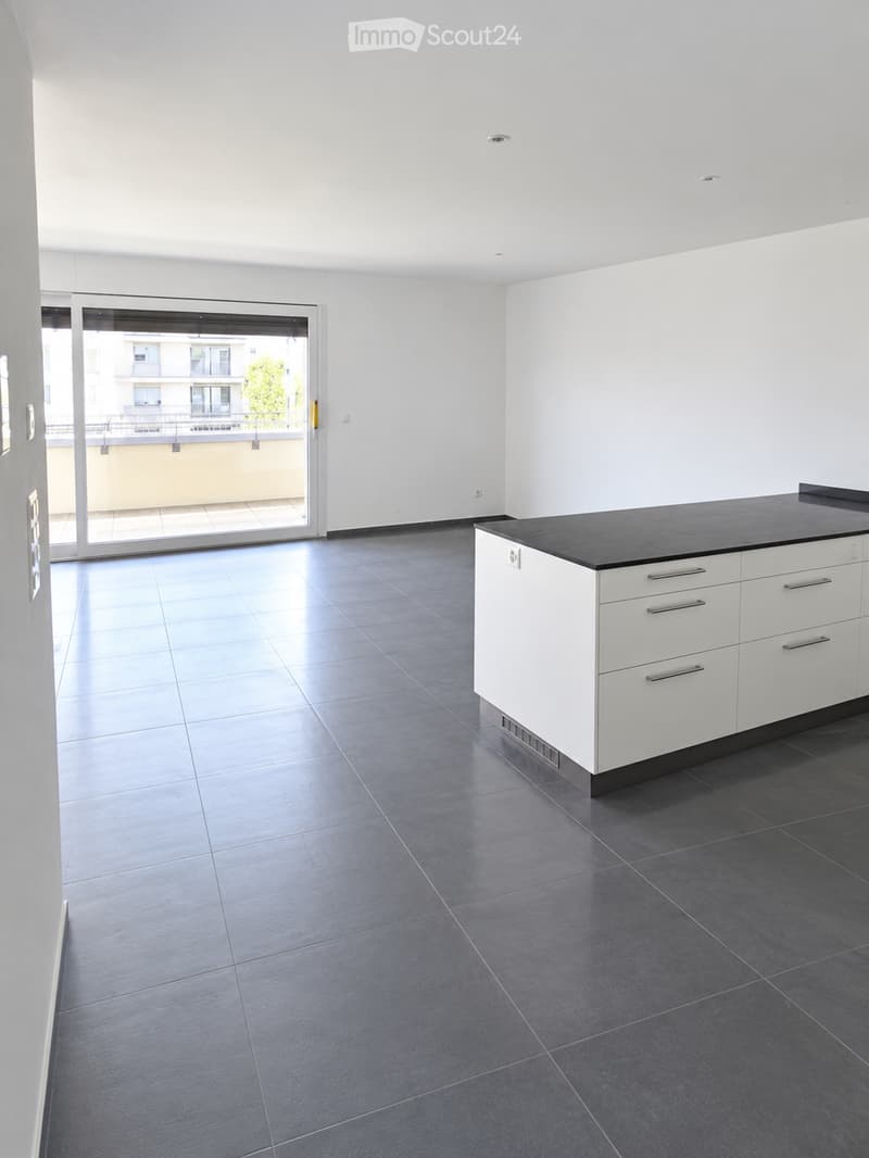 Modern kitchen with white cabinets, dark countertops, and tiled flooring. Features a large sliding glass door leading to a balcony.