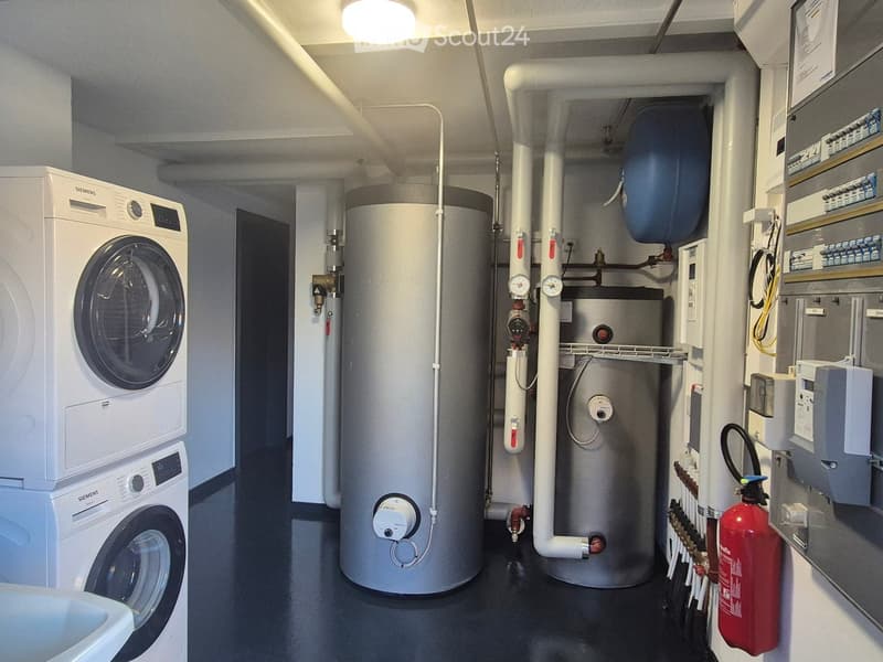 Utility room with a washing machine, water heater, and a fire extinguisher mounted on the wall.