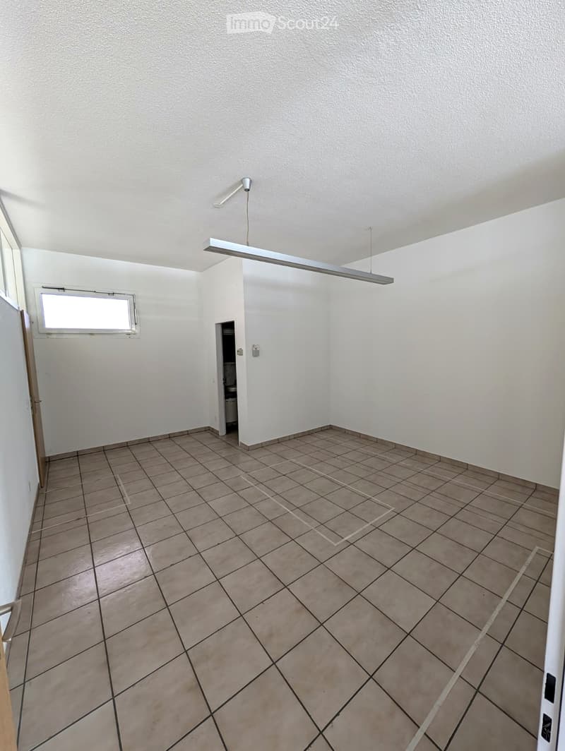 Empty room with tiled floor and white walls, featuring a window, a door, and a visible light fixture on the ceiling.