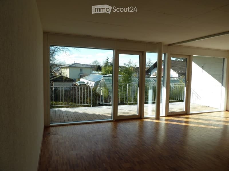 empty room with large glass sliding doors, wooden floor, balcony, large windows, outside view of neighborhood