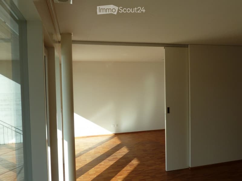 Empty room with sliding doors, wooden floor, and a balcony
