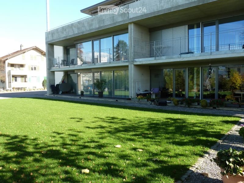 2 story house, large glass windows, concrete walls, balconies, lawn with plants
