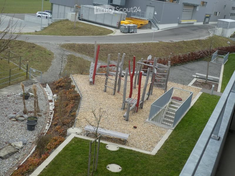 Playground with climbing frame, slide, and benches, gravel and grass areas, small trees, and plants