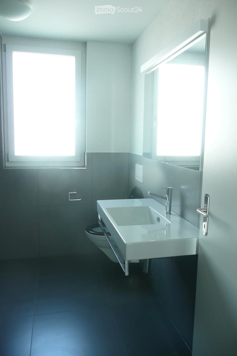 Bathroom with white sink, silver faucet, mirror, toilet, window, and tiled floor