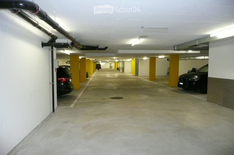 underground parking lot, yellow pillars, white walls, cars parked