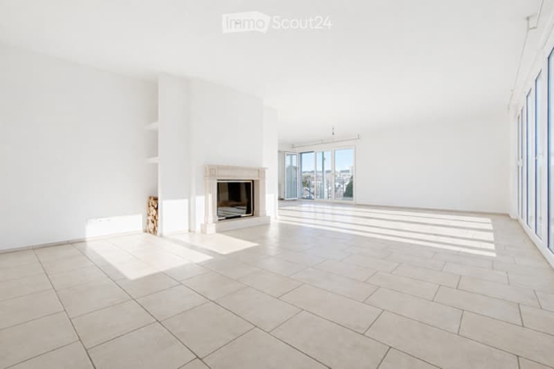 Bright, empty room with large windows offering a view, a fireplace, and tiled flooring.