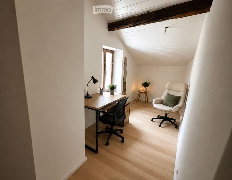 Bright, minimalist room with wooden flooring, slanted ceiling, and exposed wooden beam. Features a desk with a chair, a small table with a plant, and a white armchair with a green pillow.